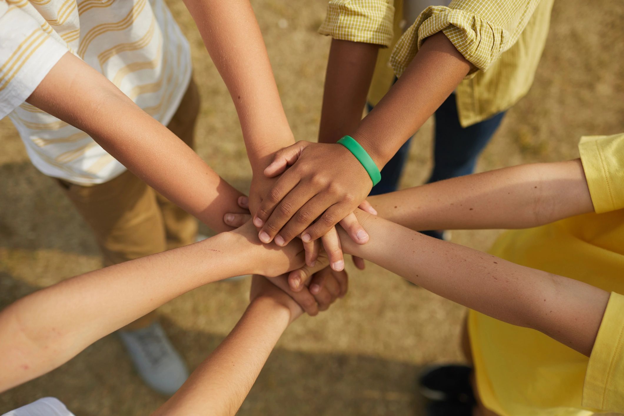 Youth stacking hands in a circle, symbolizing unity
