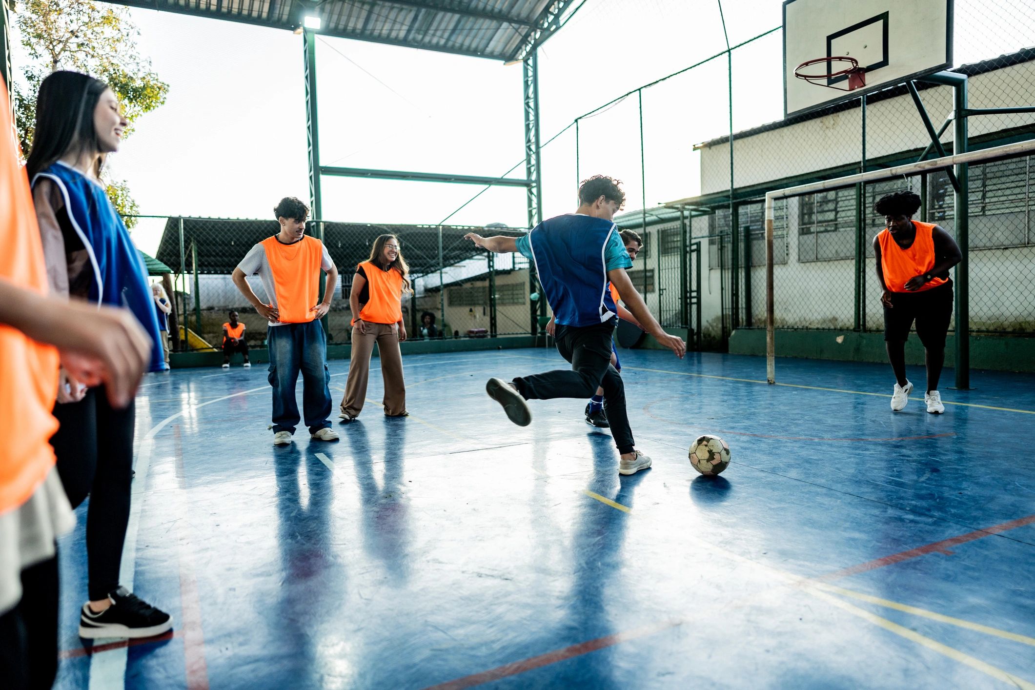 Youth playing soccer together on a school sports court