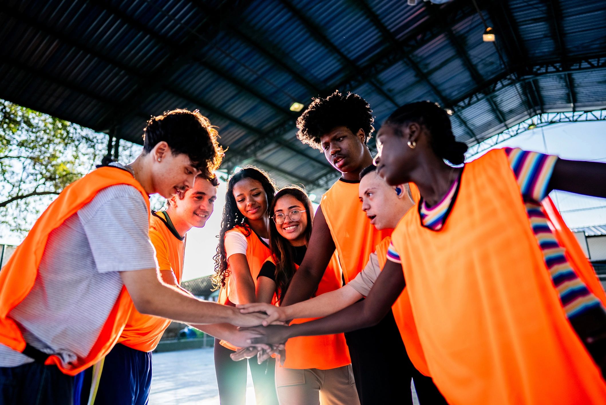 Youth soccer team huddling with hands together on a school sports court