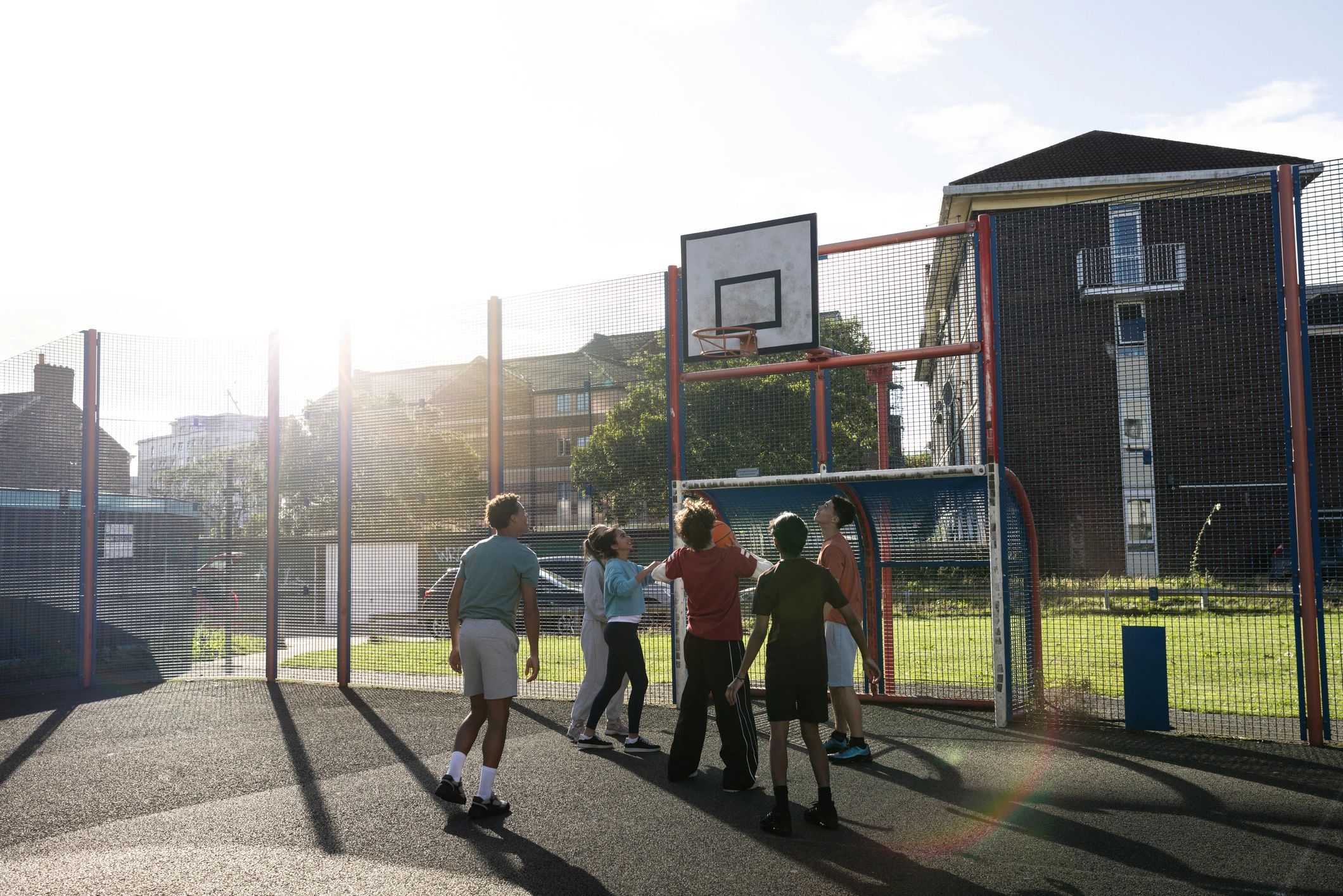 Teens playing basketball together on an outdoor court